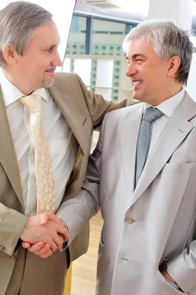 Portrait of two businessmen handshaking. Office background. — Stock Photo, Image