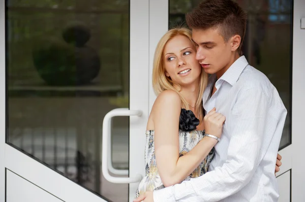Затишна молода пара обіймається вдома біля дверей і дивиться на вулицю — стокове фото