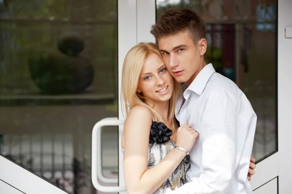 Acogedora pareja joven abrazándose en casa cerca de una puerta y mirando hacia fuera —  Fotos de Stock