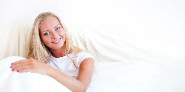 Νεαρή ξανθιά γυναίκα απολαμβάνοντας ένα ηλιόλουστο πρωινό στο κρεβάτι — Φωτογραφία Αρχείου