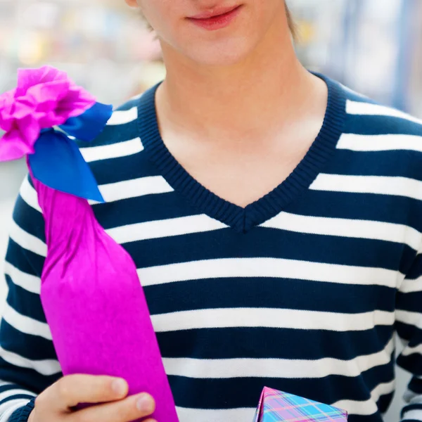 Portrait of a man with a gift box and bottle at shopping mall or — Stock Photo, Image