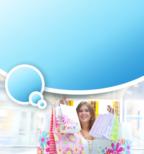 Mulher de compras com lotes de sacos sorri dentro do shopping. Ela está feliz. — Fotografia de Stock