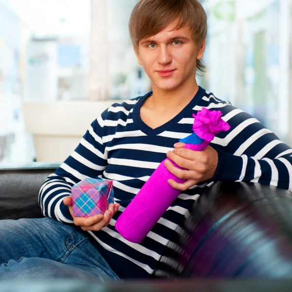 Portrait of a man with a gift box and bottle at shopping mall or — Stock Photo, Image