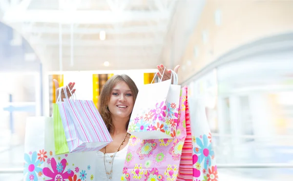 Покупательница с кучей сумок улыбается в торговом центре. She is happ — стоковое фото