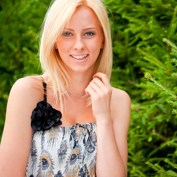 Portret van een sexy jonge vrouwelijke glimlachend in een park tegen fir tr — Stockfoto