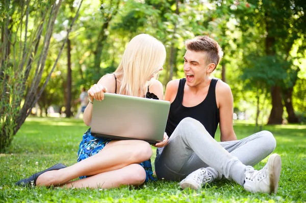 年轻快乐微笑夫妇与便携式计算机在野餐 — 图库照片