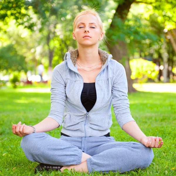 Portrait of young woman meditating in pose of lotus on green gra — Stock Photo, Image
