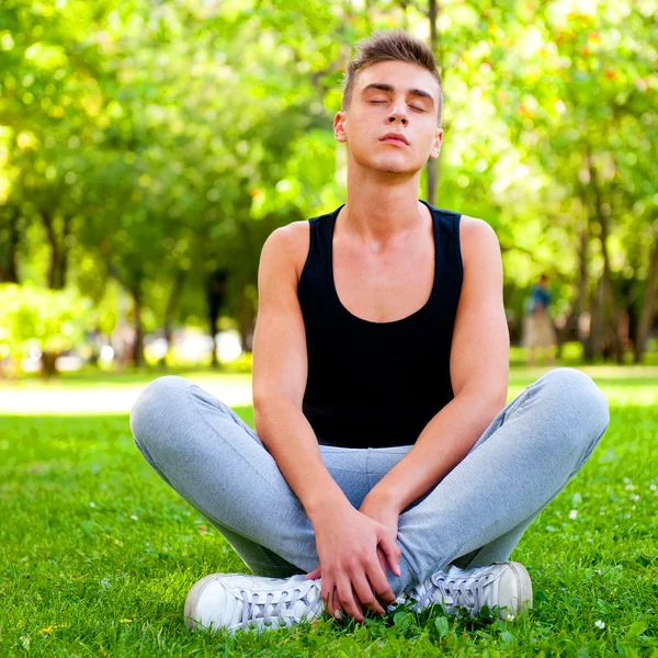 Красивый молодой человек в позе медитации на открытом воздухе . — стоковое фото
