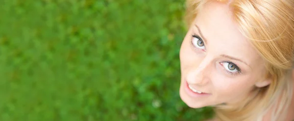 Lächelnde schöne Frau, die auf Gras liegt — Stockfoto