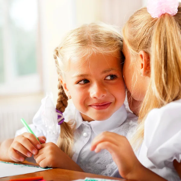 Zwei kleine Mädchen tratschen im Klassenzimmer — Stockfoto