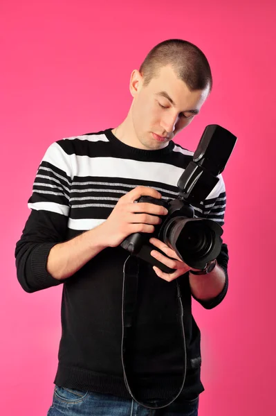 Hombre sosteniendo la cámara profesional con flash contra el backgrou rosa —  Fotos de Stock