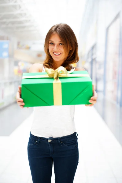 Schöne brünette Frau mit einer Geschenkbox, die in Shoppi steht — Stockfoto