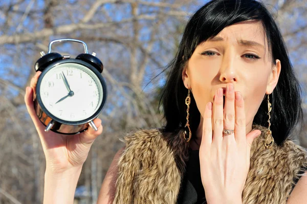 Surprised woman holding alarm clock outdoors — Stock Photo, Image