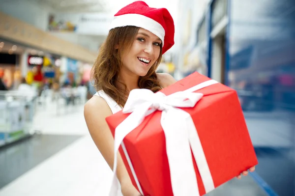 Excited attractive woman with big gift box standing at shopping Stock Image
