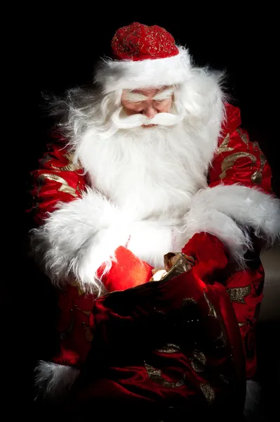Babbo Natale seduto nella stanza di Natale e guardando nel sacco — Foto Stock