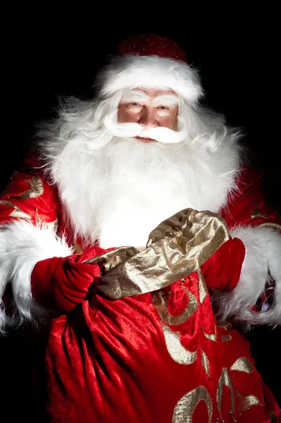 圣诞老人坐在圣诞房间和寻找进袋子 — 图库照片