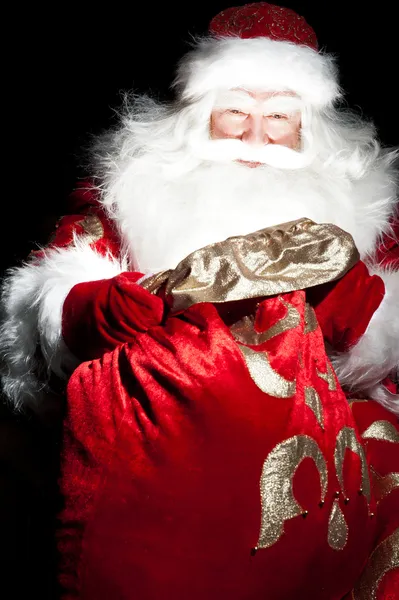 Santa sedí u vánoční pokoj a při pohledu do pytle — Stock fotografie