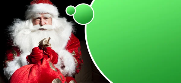 Santa sitter vid jul rum och tittar in i säcken. b — Stockfoto