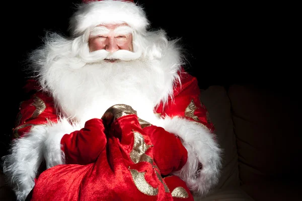 圣诞老人坐在圣诞房间和寻找进袋子 — 图库照片