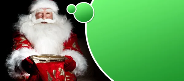 Santa sitter vid jul rum och tittar in i säcken. b — Stockfoto