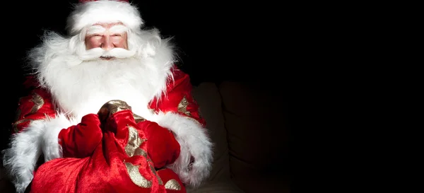 Санта сидять в кімнаті Різдва і дивлячись в мішку — стокове фото