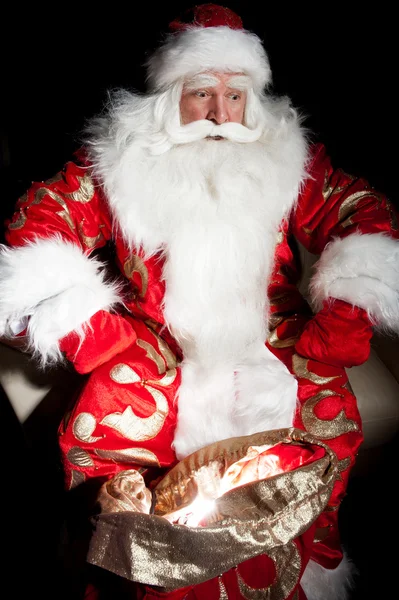 Santa sentado en la habitación de Navidad y mirando en el saco — Foto de Stock