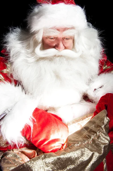 Santa zit op de kerst-kamer en op zoek naar de zak — Stockfoto