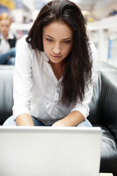 Retrato de una hermosa mujer joven que trabaja en el ordenador portátil mientras se sienta — Foto de Stock