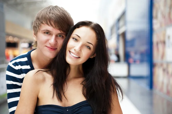 Portrait of young couple embracing at shopping mall and looking Royalty Free Stock Photos