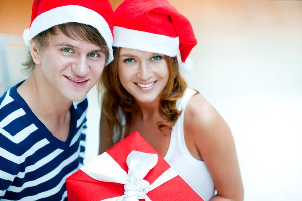 クリスマスの幸せなカップル一緒に立っていると holdi を帽子します。 — ストック写真