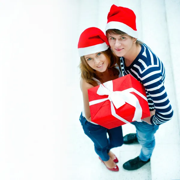 Νεαρό ζευγάρι χαρούμενος σε Χριστούγεννα καπέλα συνεργαζόμενα και holdi — Φωτογραφία Αρχείου