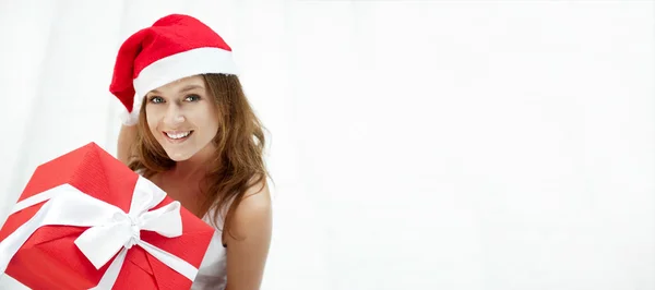 Young happy girl in Christmas hat. Standing indoors and holding — Stock Photo, Image