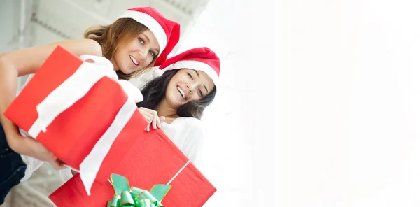 Young happy girls in Christmas hats.Standing together indoors an — Stock Photo, Image