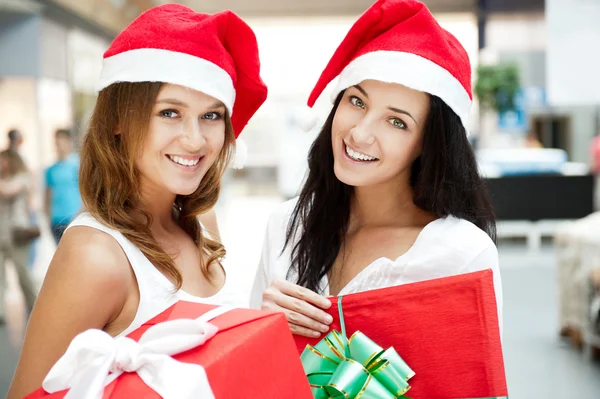 Young happy girls in Christmas hats.Standing together indoors an — Stock Photo, Image