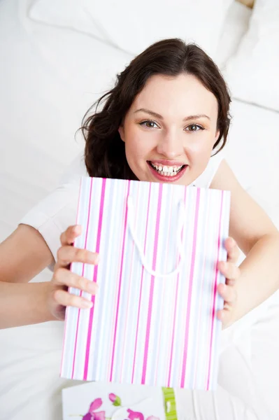 Portrait of young beautiful awake woman with gifts on bed at bed — Stock Photo, Image