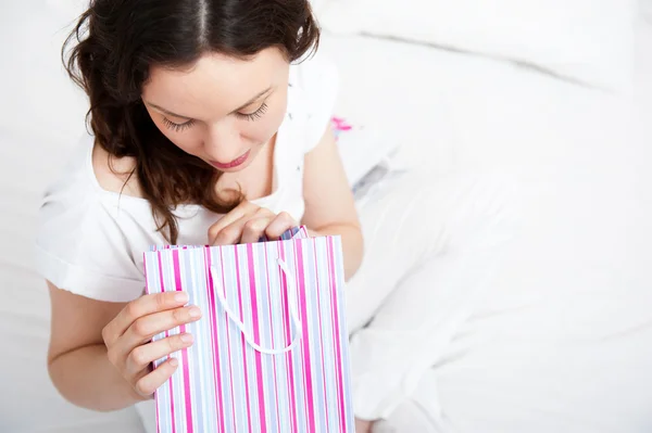 Ritratto di giovane bella donna sveglia con regali sul letto a letto — Foto Stock