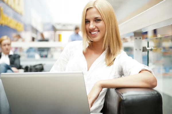 Retrato de mulher loira feliz usando laptop no shopping center café — Fotografia de Stock