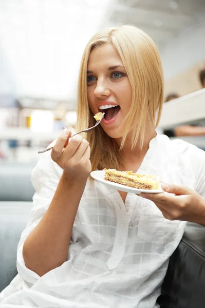Portrait of young pretty smiling woman eating cake at shopping m — Stock Photo, Image