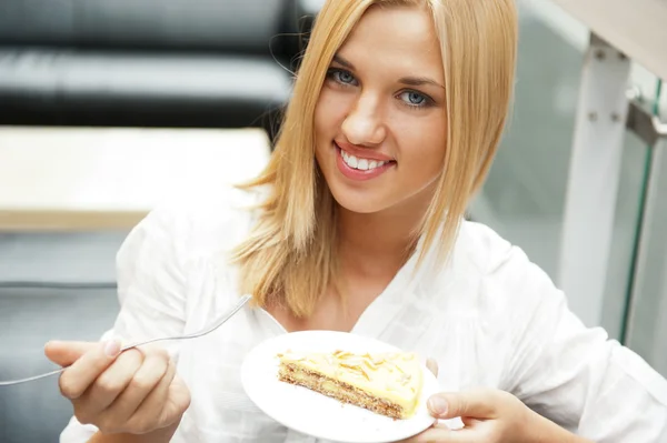 Портрет молодой красивой улыбающейся женщины, поедающей торт в магазине — стоковое фото
