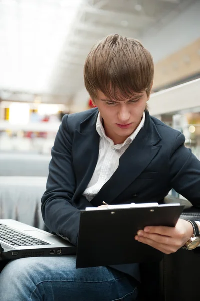 Portret van knappe jonge man met laptop werken bij café in bu — Stockfoto