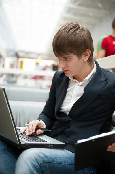 Retrato del joven guapo que trabaja con el ordenador portátil en la cafetería en bu — Foto de Stock
