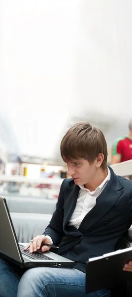Portrét pohledný mladý muž pracující s přenosným počítačem v kavárně v bu — Stock fotografie