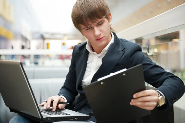 Portret van knappe jonge man met laptop werken bij café in bu — Stockfoto