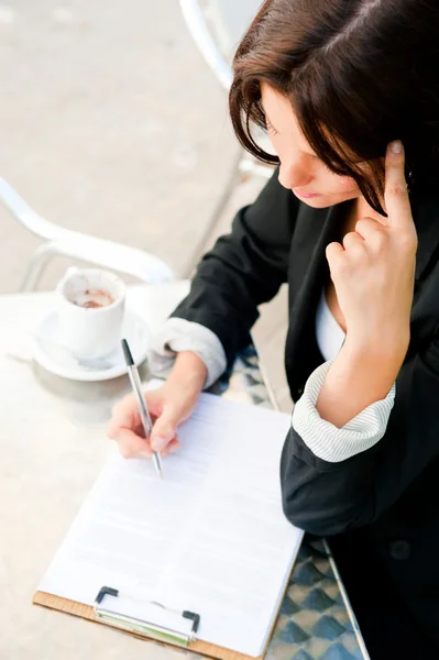 Портрет крупным планом красивой женщины, сидящей в кафе и подписывающей документы — стоковое фото
