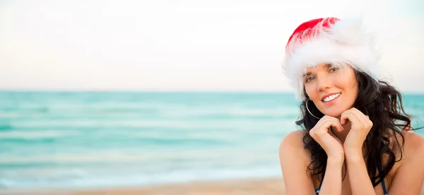 Noel şapka gösteren kalp şekli giyen genç güzel kadın — Stok fotoğraf