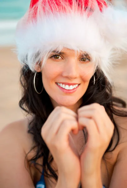 年轻漂亮的女人戴着圣诞帽显示心的形状 — 图库照片