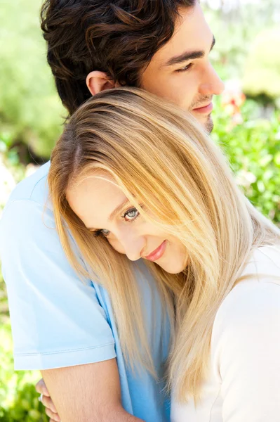 Портрет влюбленной пары, обнимающей на открытом воздухе в парке, выглядящей счастливой — стоковое фото