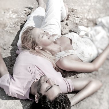 Young couple relaxing on sand at beach and daydreaming with thei clipart