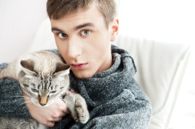 Relaxed man sitting on armchair holding and petting pet cat clipart