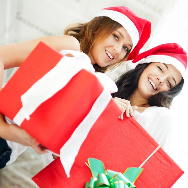 Jovens meninas felizes no Natal hats.Standing juntos dentro de casa e segurando b — Fotografia de Stock